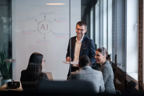 Colleagues in office discussing AI strategy with spider diagram on white board.