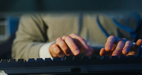 Close up of employee typing on keyboard, symbolising keystroke logging.
