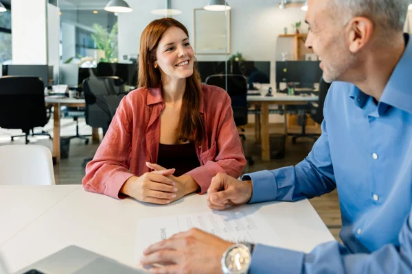 An HR professional sits at a desk chatting with a business owner.